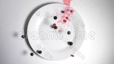 红色和黑色的醋栗浆果掉进一个漂亮的<strong>盘子</strong>里。 慢动作的醋栗落在白色的<strong>盘子</strong>顶上。